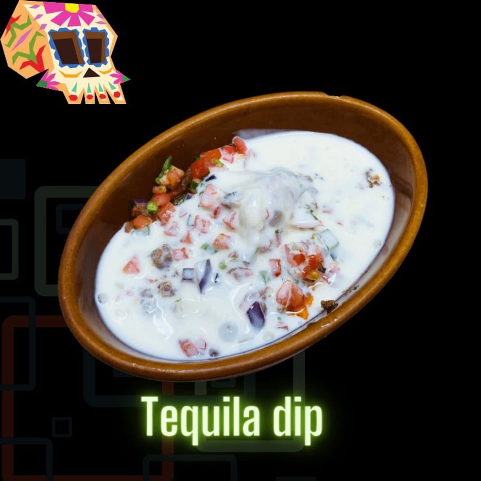 A brown bowl filled with creamy white Tequila dip, topped with diced tomatoes, onions, and ground beef.
